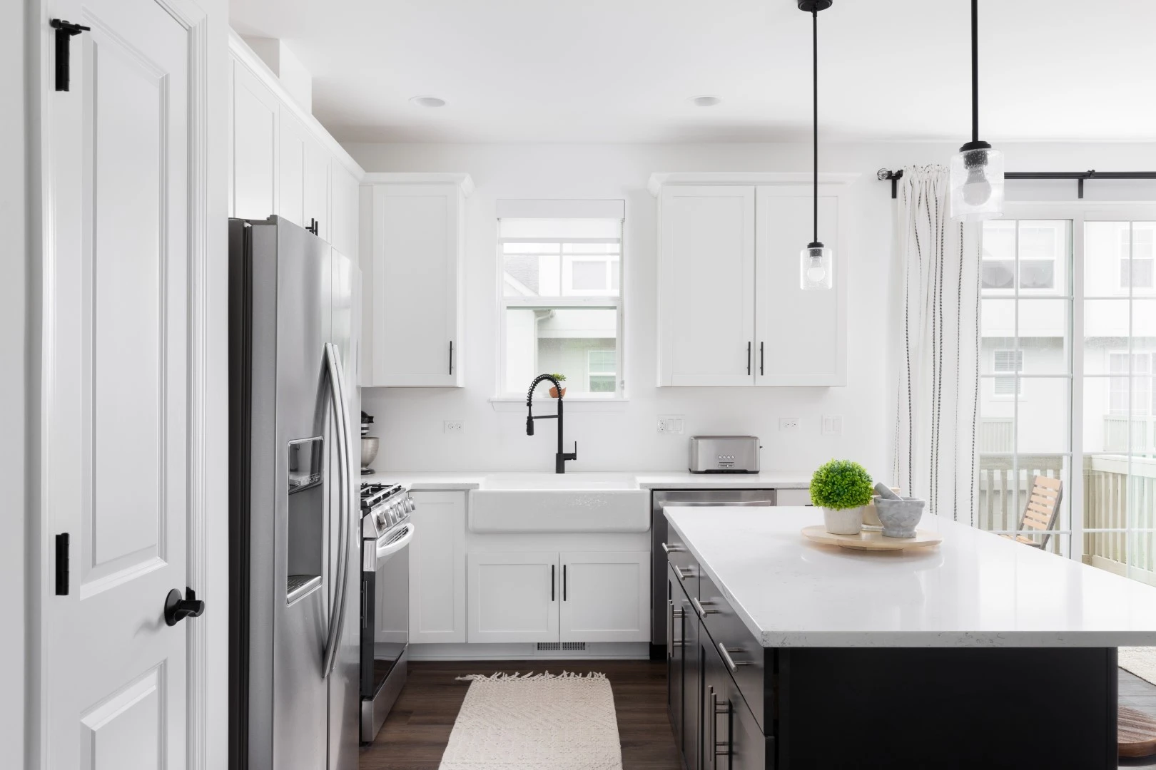 Modern kitchen remodel with white cabinets, quartz countertops, black fixtures, and pendant lighting